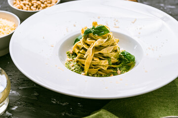 Fituccine pasta with basil and pine nut pesto on a white plate with a fork. Fituccine al pesto...