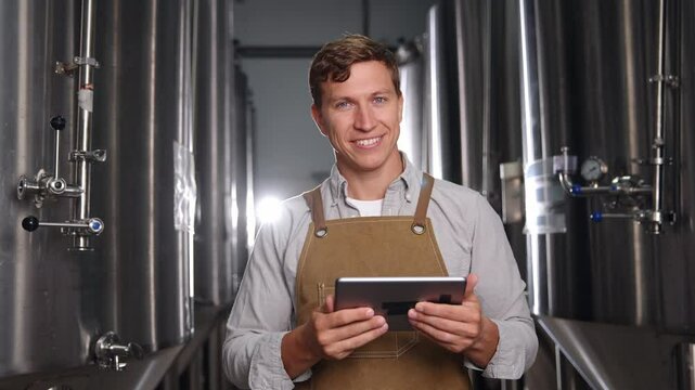 Portrait worker man on food factory, Smiling brewer utilizing tablet in modern brewery production process