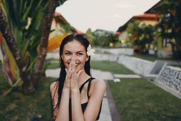 Young woman posing with hands on face and flower in hair for a beautiful and natural portrait shot