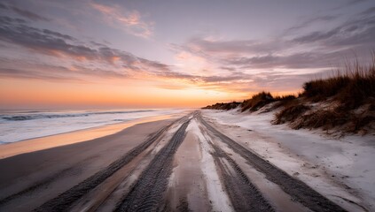 Fototapeta premium A wide sandy beach stretches out towards the horizon under a sky filled with soft pink and orange hues at sunset