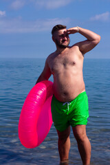 Vertical street photo. Full body young adult tanned fat white man with stubble, big belly, bright...