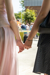 Mother and daughter holding hands during graduation ceremony, showcasing a moment of pride and...