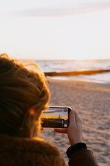 woman takes pictures of the ocean on her mobile phone.
