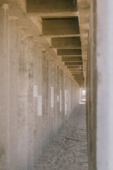 Long, narrow hallway with concrete pillars. The pillars are grey and the hallway is empty. Scene is amber and quiet. a building on the beach to protect the coastline from waves, breakwaters.