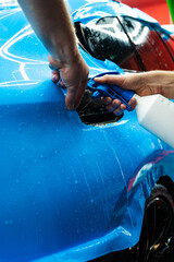 Detailing experts use hydration spray for controlled application of blue PPF film. Detailer uses...