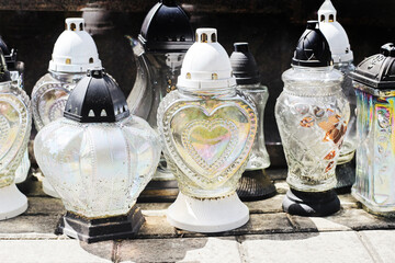 Cemetery glass candle lanterns. Graveyard memorial candles standing on stone slabs. Traditional...