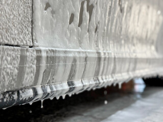 Process of spraying foam on the auto body in the station. Second phase of detailing washing in car service.  Cleaning the car using high pressure water. Car washer does full body car wash with soap. 