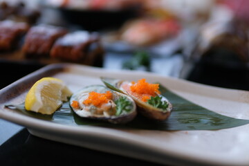 Fresh oyster arranged on ice and garnished with green herbs on round dish with crispy fried onion, seafood sauce and chili paste. High quality photo