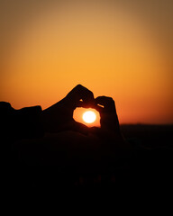 Hands Making Heart Silhouette At Sunset with Orange Sun