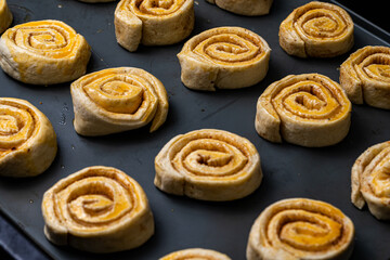 Making homemade cinnamon puff text buns. The brush greases raw dough rolls with egg yolk.