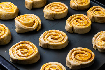 Making homemade cinnamon puff text buns. The brush greases raw dough rolls with egg yolk.