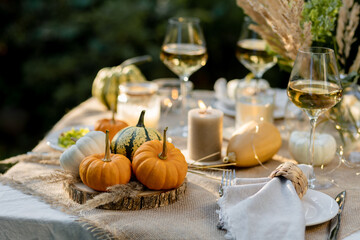 Fall still-life. Orange pumpkins, dry flowers and candles on linen tablecloth. Dinner table...