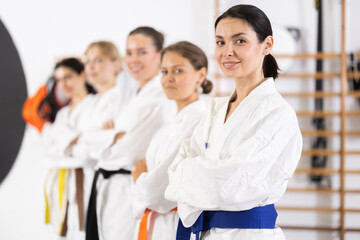 Side view of positive young woman standing in row in sports hall