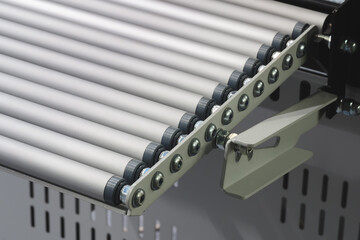 Conveyor belt with a white handle on the end. belt is made of metal and is silver in color
