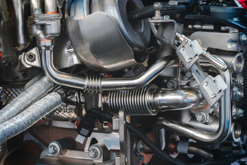 Obraz premium Part of car engine with many tubes and parts, car service concept background