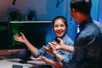 Dedicated programmers developing artificial intelligence solutions late at night collaborating on...