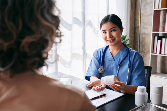Asian Adult Woman Doctor Explaining Medication Benefits To Patient During Consultation In Clinic For Healthcare