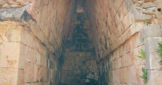 Ancient stone chamber with steep walls at an archaeological site of Mayan ruins