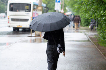 It's raining in the city. A man with an umbrella is walking through the city.