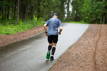An old man is running in the park. Outdoor fitness.