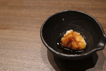 ポン酢をかけた大根おろしの小鉢と木のテーブル