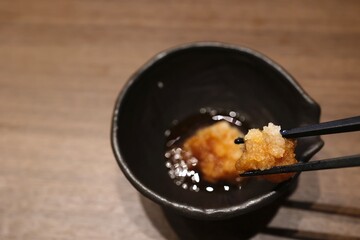 ポン酢をかけた大根おろしの小鉢と木のテーブル