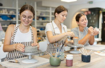 During working day, three employees of pottery workshop molding from clay, paint finished product....