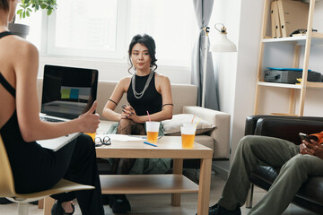 Young woman in black dress working with colleagues in a modern workplace, socializing and...