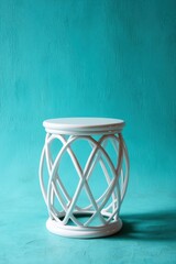 White rattan stool against a turquoise wall, simplistic and clean
