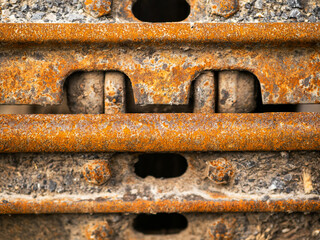 The rusty tracks of a machine are shown in the image. The tracks are old and worn, and the machine...