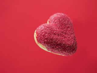 Red creative heart shaped donut floating in the air, red color saturated background. Love and...