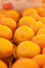 A vibrant and colorful close-up shot of ripe oranges stacked in a wooden crate at a market.