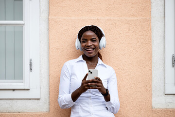 Portrait of happy black girl tourist walking through the city and using smart phone.