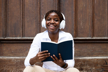 Portrait of smiling black female student holding a book at college.