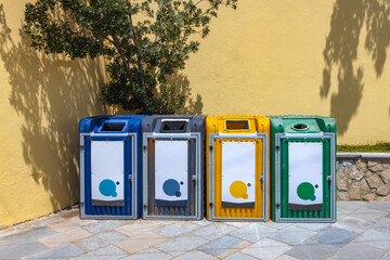 Public recycling containers and outdoor recycling station set up by the sea. Eco-friendly waste disposal bins standing on clean beach sand.