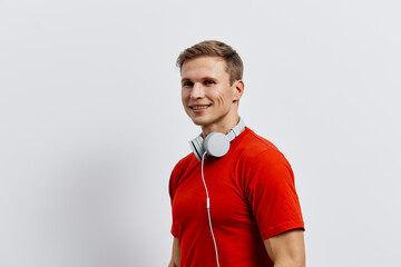 Smiling young man with headphones wearing red t-shirt, casual style, cheerful and friendly...
