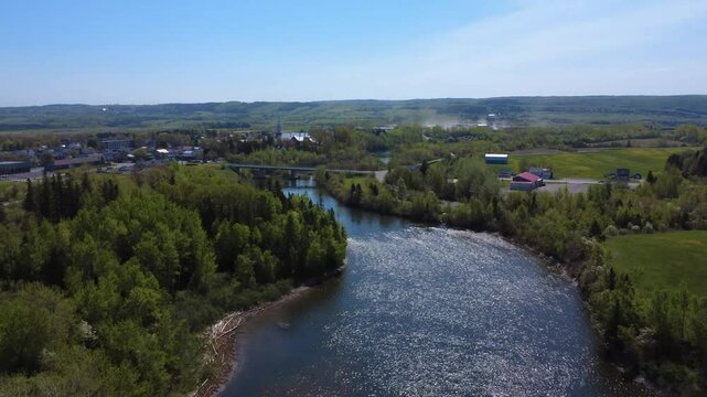 Aerial view of the municipality of Price surrounded by forest, featuring its church near a road bridge spanning the Mitis salmon river, Quebec, Canada.