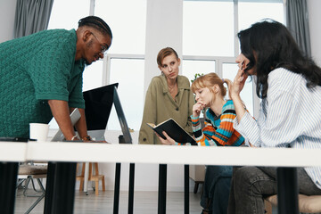 young adult woman and diverse colleagues collaborating in workplace focused on business,...