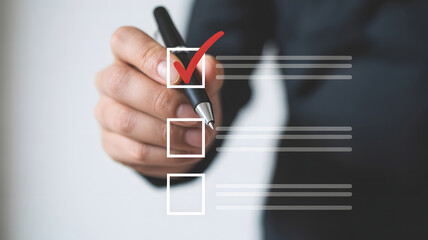 A businessman marks a checklist box with a red check, representing task completion, agreement, and positive confirmation of the selection process and successful achievement.