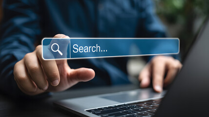 Person's hand touches search bar on laptop computer, symbolizing online searching, information access, technology use, browsing, and internet connectivity for research and digital engagement.
