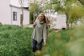 Middle age woman enjoys healthy active lifestyle walking outdoors wearing warm sweater in spring green garden