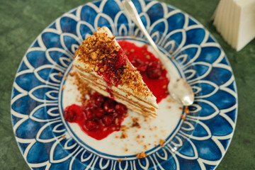 Honey cake with cherries on decorative plate with blue pattern, Tasty dessert 