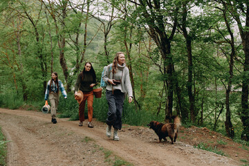 Middle age woman walking with friends and dog in forest, enjoying active healthy lifestyle,...
