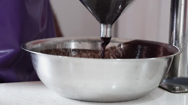 Acai pulp dripping from the machine after the traditional beating process, showing the rich texture and color of the fruit separated from the seed