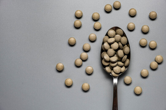 Round green tablets of iron supplements on gray background. Health medication