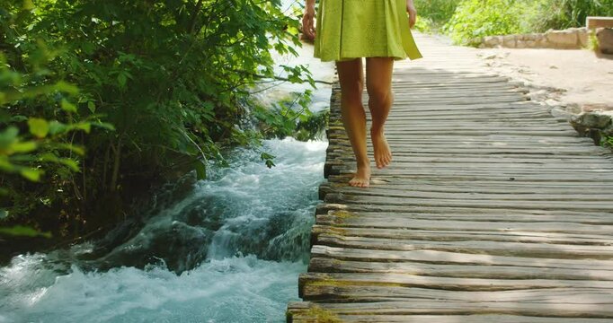 Barefoot woman walking over rushing stream in Plitvice in summer