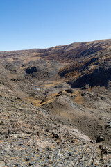 Expansive rocky landscape with rugged terrain and distant hills under a clear blue sky, showcasing the beauty of nature and geological formations in a remote area