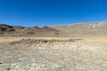 Expansive arid landscape featuring rocky formations under a clear blue sky, showcasing the beauty...