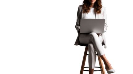 Professional woman working on a laptop while sitting on a stool in a modern office setting.