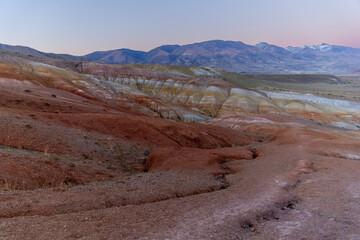 Colorful layered hills in a vast arid landscape, showcasing unique geological formations and...